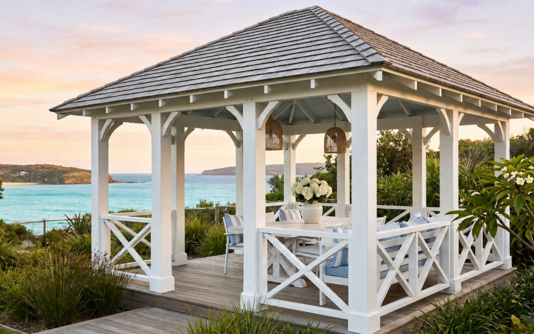 A white Hamptons style gazebo with a shingle roof and cross-braced railings overlooking the ocean.